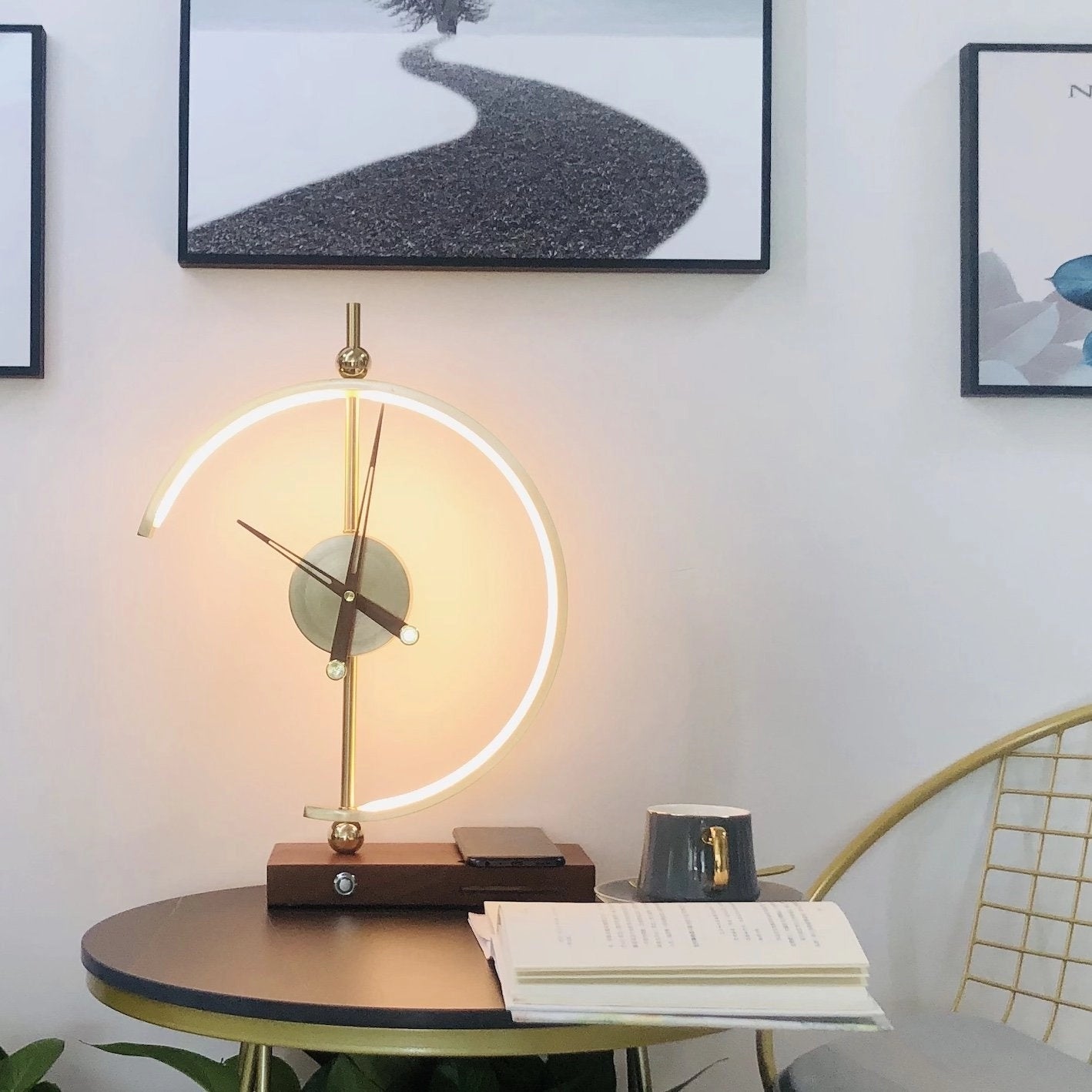 A modern wireless charging clock lamp with an LED light and integrated clock placed on a wooden table in a stylishly designed room.