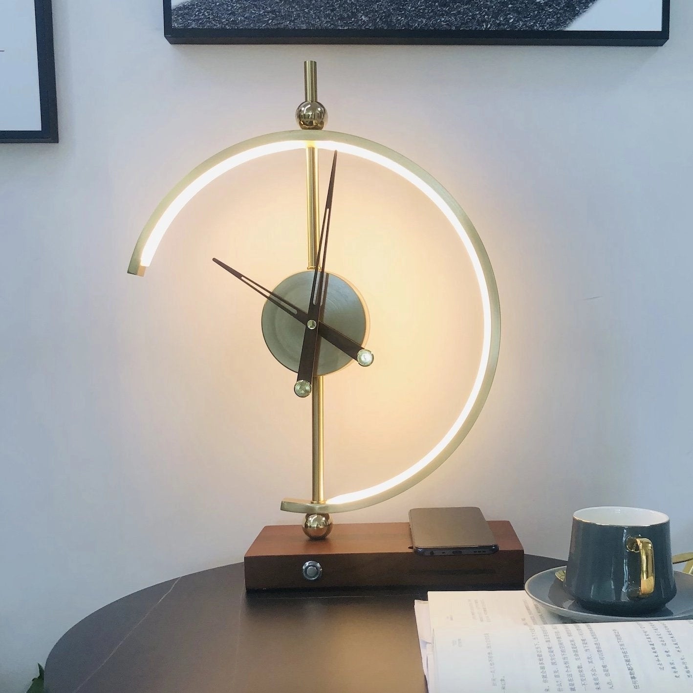 A modern wireless charging clock lamp with LED light, integrated clock, and wooden base, placed on a table next to a ceramic coffee cup.